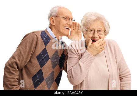 Elderly man whispering to a surprised elderly woman isolated on white background Stock Photo