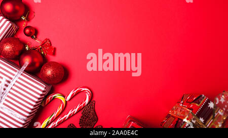 Christmas and New Year red background decorated gift boxes, Santa hat and toys. Banner Stock Photo