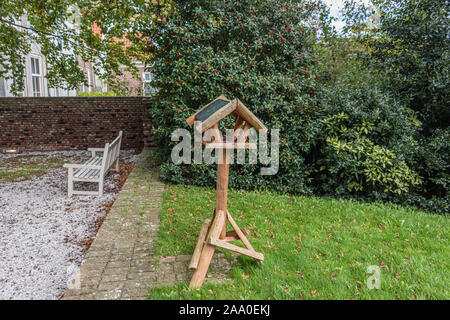 new birdhouse for feeding the birds mounted on a wooden pole Stock Photo