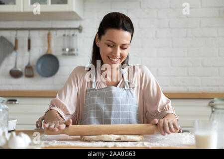 Portrait happy ideal housewife rolling out dough. Stock Photo