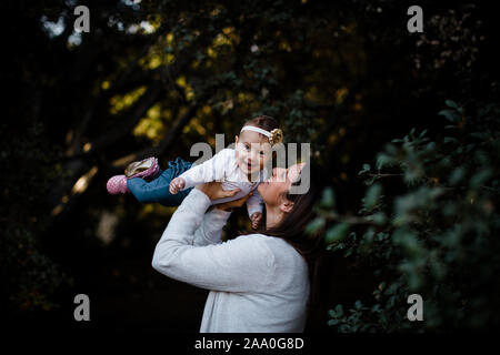 Mom Lifting Daughter as Baby Smiles Stock Photo