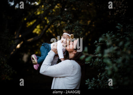 Mom Kissing Daughter as Baby Smiles Stock Photo