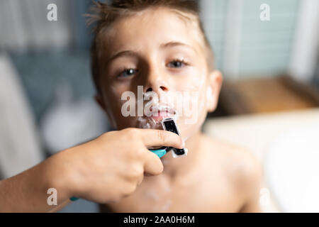 little boy shaving like an adult in the bathroom in front of the mirror Stock Photo