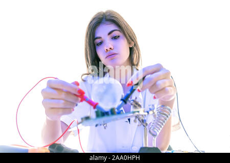 Woman Electronic Technician checks PCB with a digital Multimeter in the Service Workshop Stock Photo