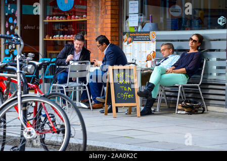 People enjoying lunch at a sushi and coffee cafe on Upper Tachbrook Street, Victoria, London, showcasing city life, food culture and outdoor dining. Stock Photo