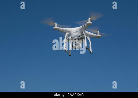Drone camera in flight against a clear blue sky. Stock Photo