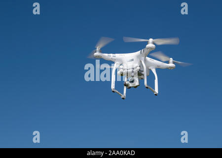 Drone camera in flight against a clear blue sky. Stock Photo