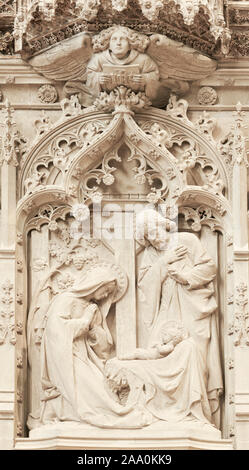 Birth of Jesus Christ (with his father and mother, Mary and Joseph, looking on) carved in stone in the english medieval cathedral at Winchester, Engla Stock Photo