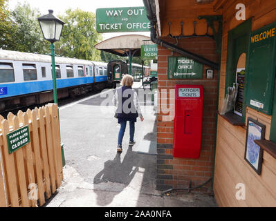 Level Crossing at Isfield Station in East Sussex with the Lavender Line station in the background with a train and signal box. Stock Photo