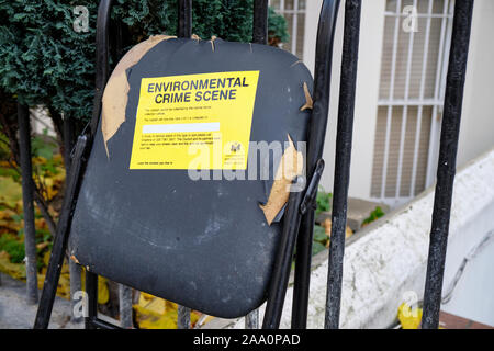 Rubbish broken chair left uncollected on sidewalk with yellow label "Environmental crime scene" from borough of Kensington and Chelsea Stock Photo