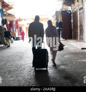 Fez, Morocco. November 9, 2019. a couple with suitcase in hand walking in the street Stock Photo