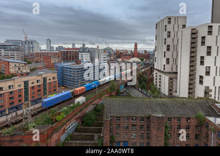 Freightliner container freight train passing Manchester Oxford Road on the congested 2 track railway through Manchester Castlefield Stock Photo