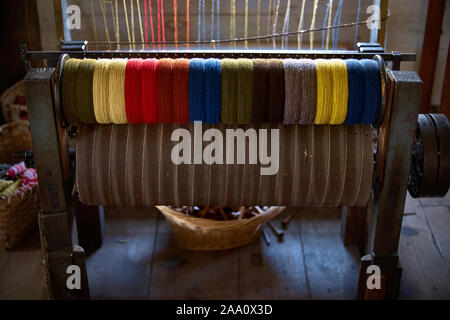 Spools of colored thread that were used in a woolen mill 1800's and early 1900's. colored woolen threads on an old loom, Traditional Yarn in Canada. Stock Photo