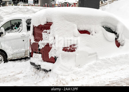 Car on a street covered with big thick snow layer after heavy snowfall. Extreme blizzard aftermath. Vehicle windshield with frozen window and wipers Stock Photo