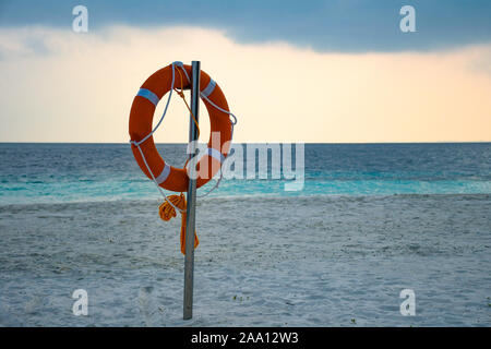 Yellow swimming rescue ring mounted on the pole on the sandy exotic beach Stock Photo