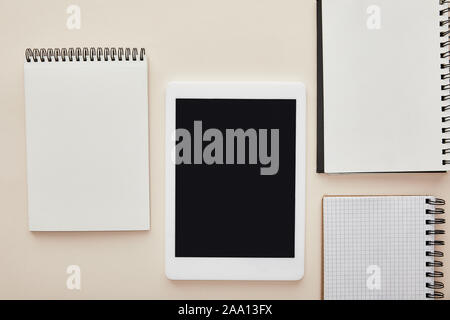 notebooks near digital tablet with blank screen isolated on beige Stock Photo