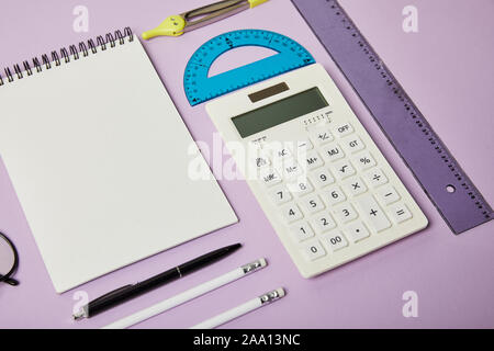rulers and calculator near notebook and pencils with pen isolated on purple Stock Photo