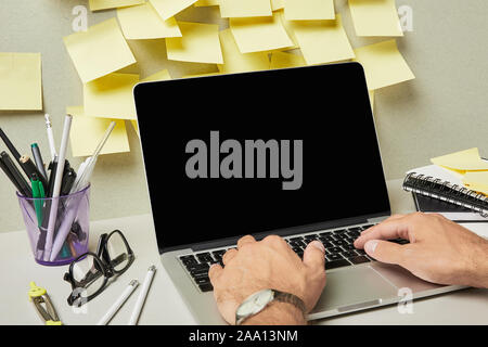 cropped view of man using laptop with blank screen near stationery and notebooks on grey and white Stock Photo