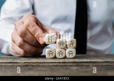 Front view of real estate agent stacking wooden dices with house symbols on them in a conceptual image. Stock Photo