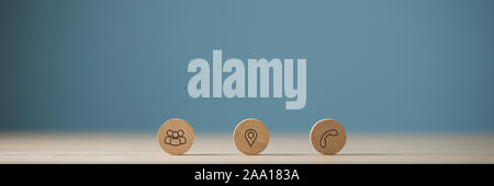 Wide view image of three wooden cut circles with contact and information icons on them placed in a row. Over blue background with copy space. Stock Photo