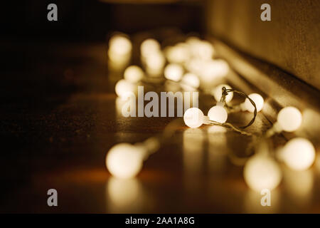 Close up view of decorative wire led small warm white light bulbs lay on a floor at corner of dark and dim room. Romantic and decoration lightbulb. Stock Photo