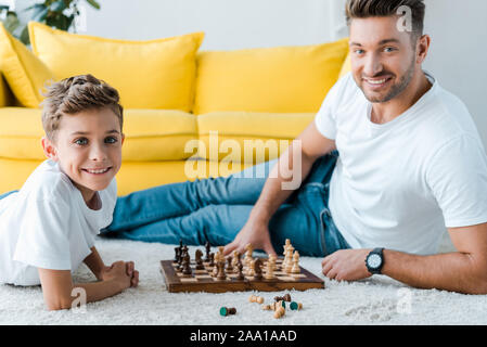 happy father and son playing chess on carpet Stock Photo