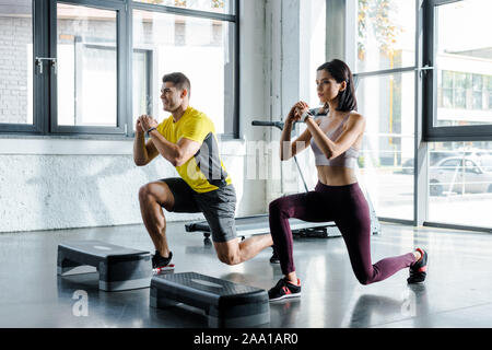 smiling sportsman and sportswoman doing lunges in sports center Stock Photo