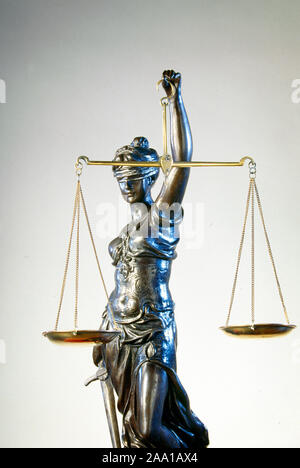 A bronze Blind Justice Statue holds a pair of balance scales. Since the 16th century, Lady Justice has often been depicted wearing a blindfold. The blindfold represents impartiality, the ideal that justice should be applied without regard to wealth, power, or other status. Stock Photo