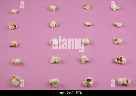 Pink surface on which there are some popcorn forming a grid. Thematic fund related to entertainment, cinema and television Stock Photo