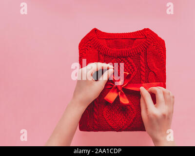 Sweater Christmas gift concept Girl is banding up red sweater with satin ribbon Template with copy space Stock Photo