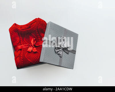 Sweater Christmas gift Warm red sweater with a traditional ornament in silver gift box with a large bow on white background Stock Photo