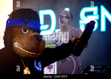 Rap singer Snoop Dogg performs with a cigar-waving costumed dog companion at an outdoor concert in Huntington Beach, CA.. Stock Photo