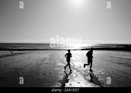 Dog walking and runners on Langland Beach in Langland Bay on the Gower Peninsular in South Wales Stock Photo