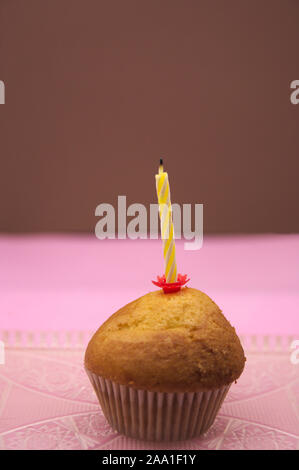 A cupcake with a candle off above with pastel colored backgrounds Stock Photo