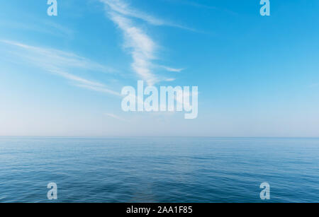 Boat cruising the sea leaving wake on a brilliant sunny day. Beautiful blue sky with light white clouds. Stock Photo