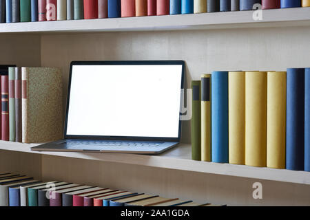 Close up of laptop in bookshelf Stock Photo