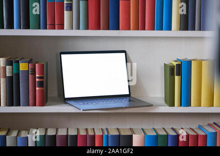 Open laptop in office, white bookshelf Stock Photo