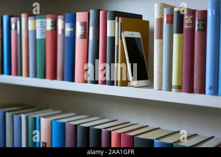 Sideview of mobile phone in bookshelf, close up Stock Photo