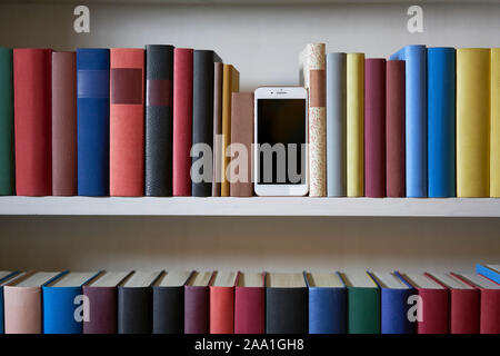 Mobile phone in bookshelf with sorted books Stock Photo