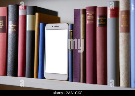 Close up of mobile phone in bookshelf, blank display Stock Photo