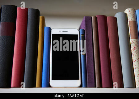 Smartphone standing upright between accurate books Stock Photo