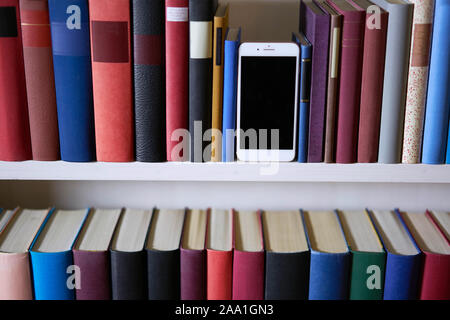 Accurate bookcase with a mobile phone standing upright Stock Photo