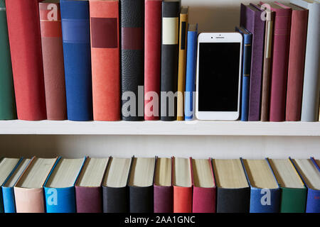 Accurate bookcase with front view of a new mobile phone Stock Photo
