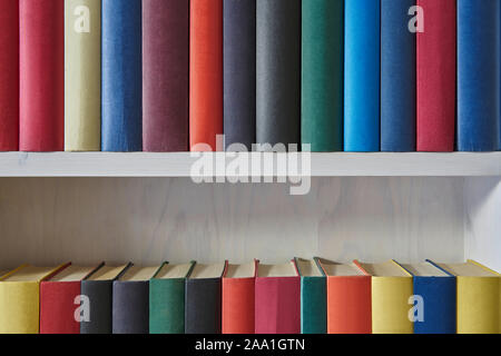 Close up of rows of books with colorful covers in a white shelf Stock Photo