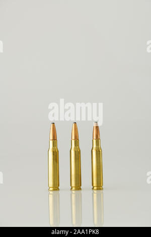 Three high power rifle bullets on high key background, objects used for terrorism, armed conflict and violence Stock Photo