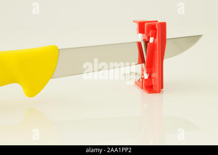 Sharpening deboning kitchen knife on mini whetstone, tool, objects, close up, concept, idea, high key background Stock Photo