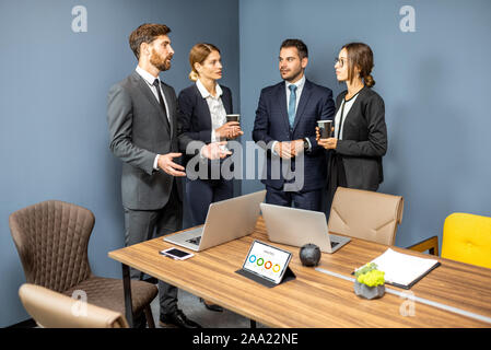 Business people having informal discussion during a coffee break in the meeting room Stock Photo
