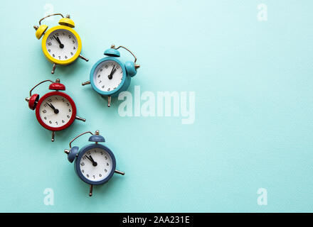 Flat lay Christmas composition with color alarm clocks  on light blue background. Stock Photo