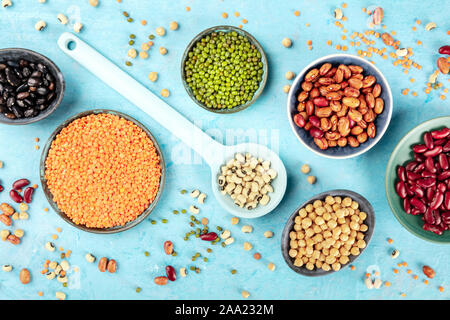 Legumes, shot from the top on a blue background. Vibrant pulses including colorful beans, lentils, chickpeas, a flat lay composition Stock Photo