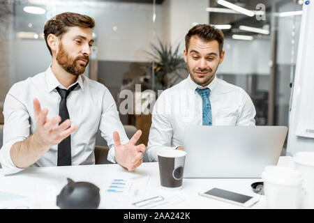 Two male employees in white shirts and tie having some business discussion in the meeting room Stock Photo